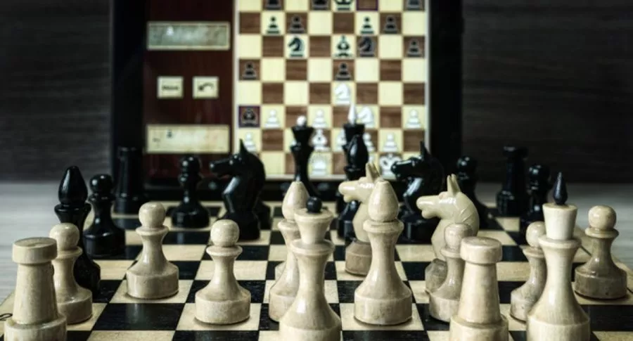 Tablero de ajedrez físico y otro virtual, ilustra nota de cierre de canal de ajedrez en YouTube por considerarlo racista