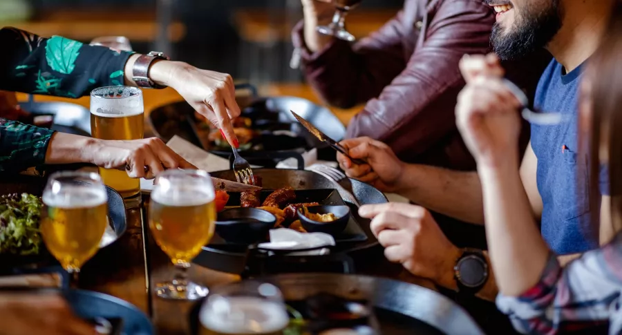 Grupo de personas comiendo y bebiendo ilustra nota sobre permiso a restaurantes para vender licor