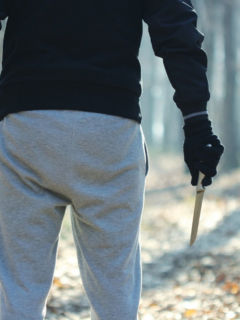 Hombre con guantes negros sostiene hacha y cuchillo en el bosque, ilustra nota de hombre que intenta sacrificar a su hijo como ofrenda a Dios, en Turquía