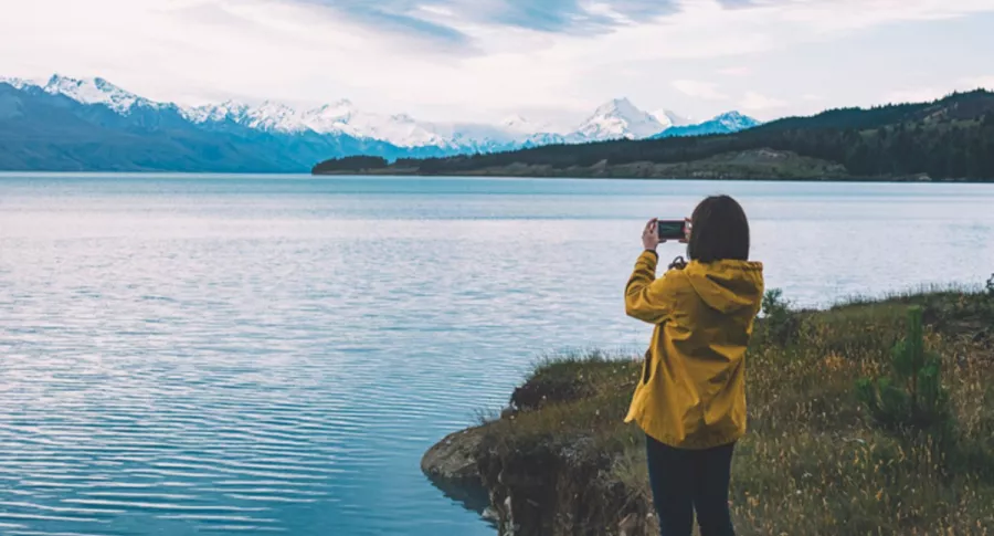 Mujer toma foto con su celular a un lago, ilustra nota de mujer recupera su iPhone funcional meses después de que se le cayó a lago
