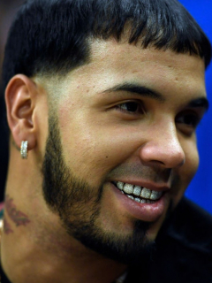 Anuel AA y captura de pantalla de video en el que se tatúa en el cuello