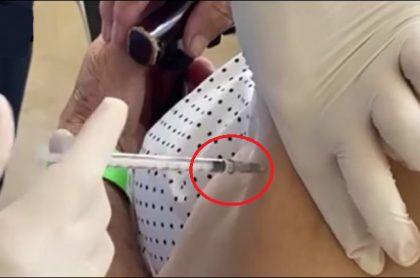 Momento en que la enfermera introduce la aguja en el brazo de una adulta mayor, pero no tiene la dosis de la vacuna