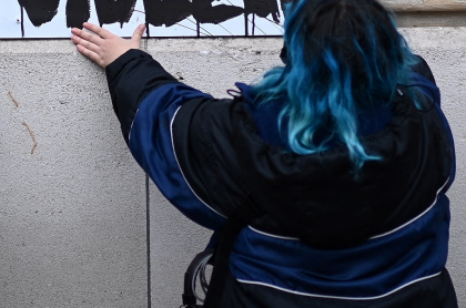 Imagen de mujer pegando afiche ilustra artículo Bogotá: aparecen carteles en contra de extranjeros en el sur