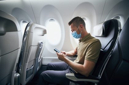 Foto de hombre con tapabocas en un avión, a propósito de medidas de Reino Unico para colombianos