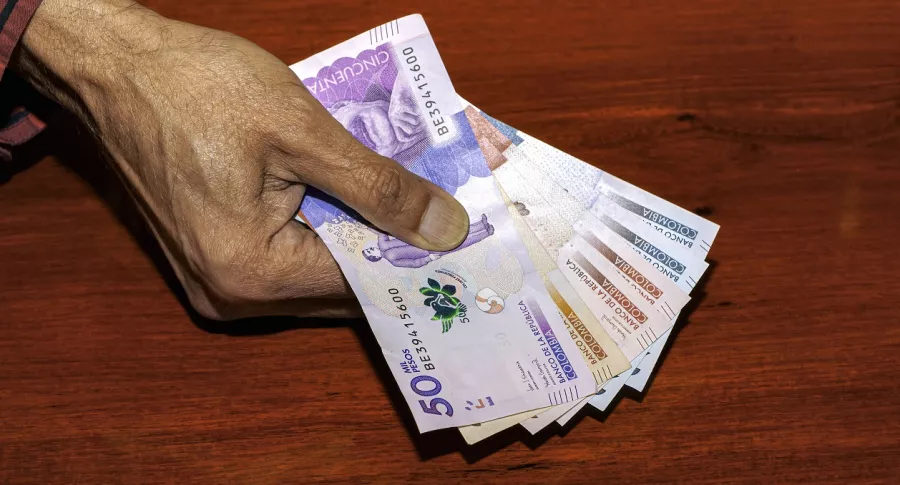 Persona con billetes colombianos ilustra nota sobre personas que podrían empezar a pagar impuesto a la renta