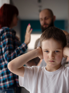 NIño tapándose los oídos mientras papás pelean