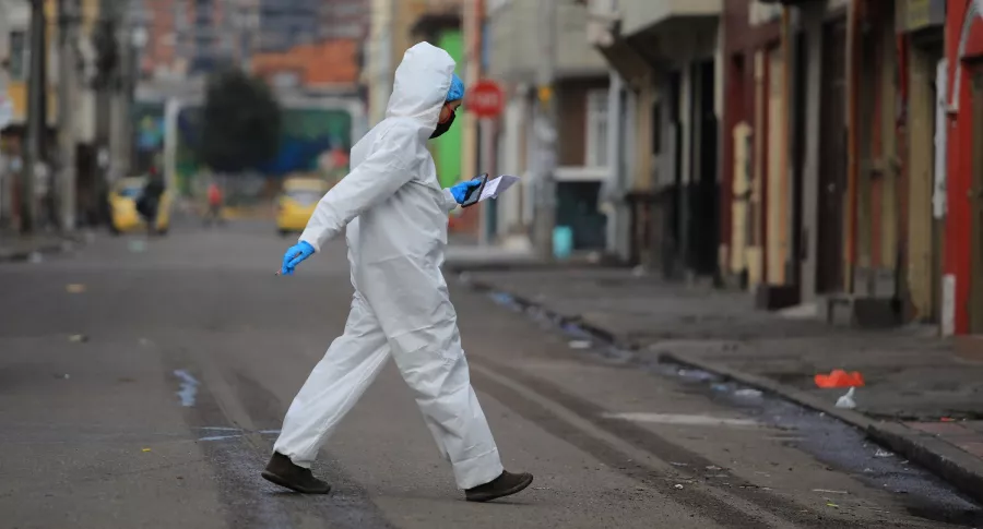 Mujer con traje antifluidos en Bogotá ilustra nota sobre semanas de incremento de casos de COVID-19 