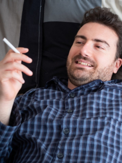 Hombre fumando acostado, ilustra nota de video de pillan a político acostado, fumando y escuchando música en sesión virtual