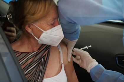 Vacunan a anciana dentro de carro, ilustra nota de Colombia pide a Estados Unidos donación de vacunas AstraZeneca