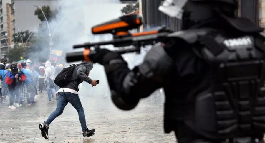 Un agente del Esmad dispara un arma antidisturbios contra manifestantes en Bogotá.