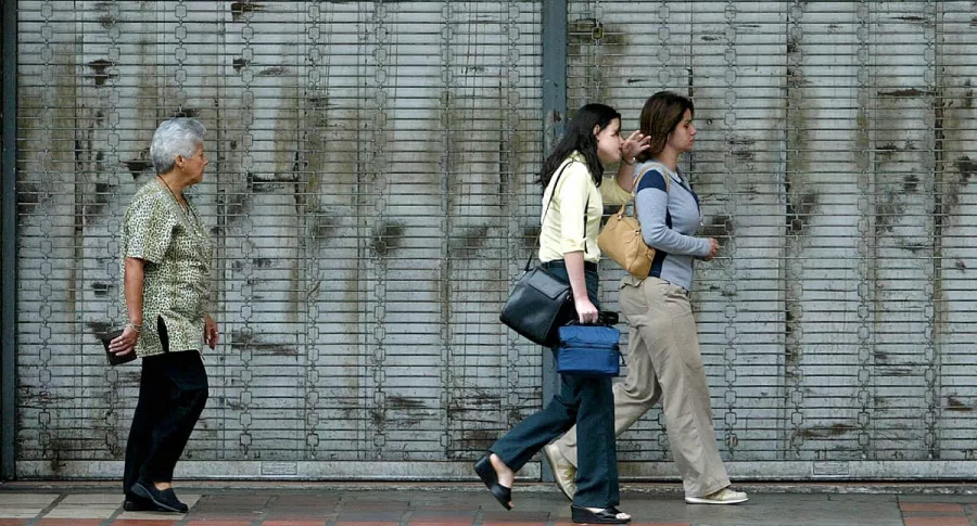 Imagen de personas caminando frente a local cerrado ilustra artículo Paro nacional: comerciantes cierran locales por amenazas, no por protestar