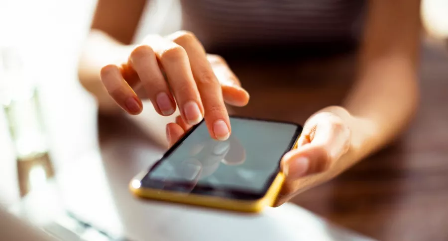 Foto de persona con dispositivo móvil en la mano en referencia a nota sobre cómo pasar contactos de una celular a otro.