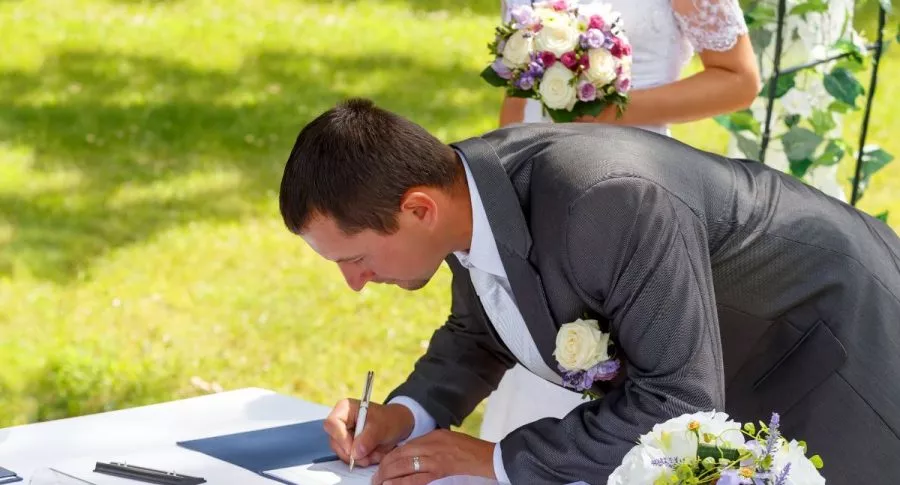 Foto de matrimonio, con esposo firmando, en referencia a nota de qué se necesita para matrimonio civil en Colombia.