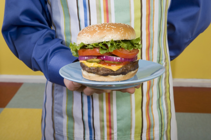 Hombre mostrando hamburguesa ilustra los errores comunes al hacer hamburguesas en casa, según el chef Juan Diego Vanegas.