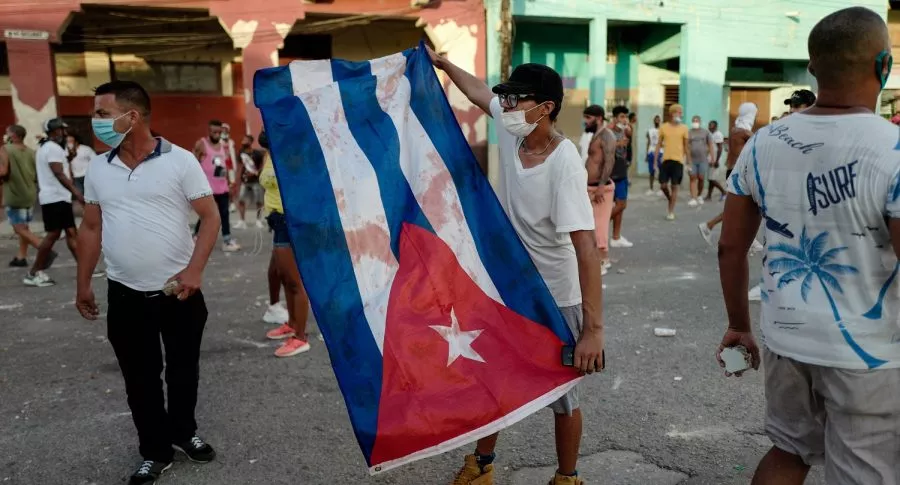 Hombre con bandera de Cuba ilustra nota sobre cuánto cuesta un paquete de pollo allá