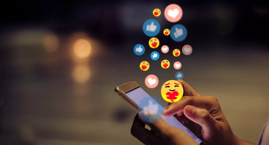 Foto de persona usando celular y con emojis, en nota de nuevos emojis pendientes de aprobación.