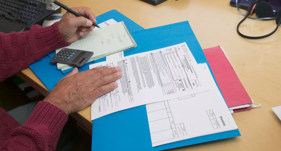 Foto de persona con documentos y calculadora, en nota de cómo hacer declaración de renta gratis con Bancolombia y plataforma Tributi.