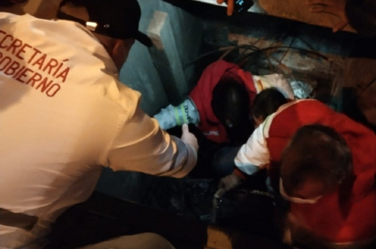Personas ayudando a funcionaria de Personería de Bogotá que cayó a alcantarilla