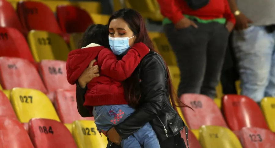 Una madre huye de la gresca ocasionada por hinchas de Nacional en el primer partido con público en Bogotá desde la pandemia.