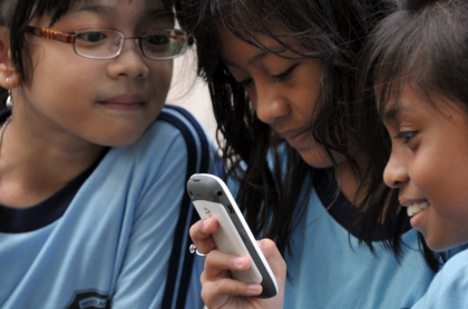 Imagen de niñas observando un celular ilustra artículo YouTube estrenan funciones para evitar que menores accedan a contenido adulto