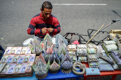 Un venezolano hace figuras con los devaluados billetes de bolívar.