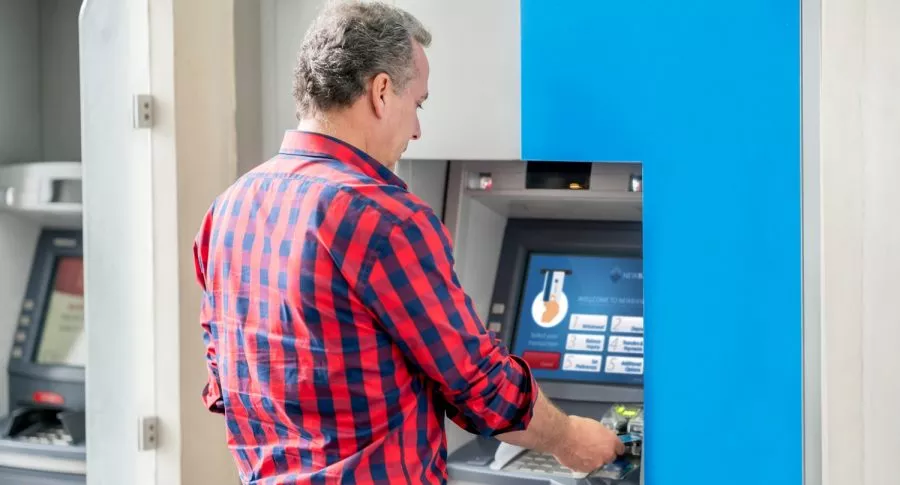 Hombre en cajero automático ilustra nota sobre cómo consultar saldo de cuenta bancaria