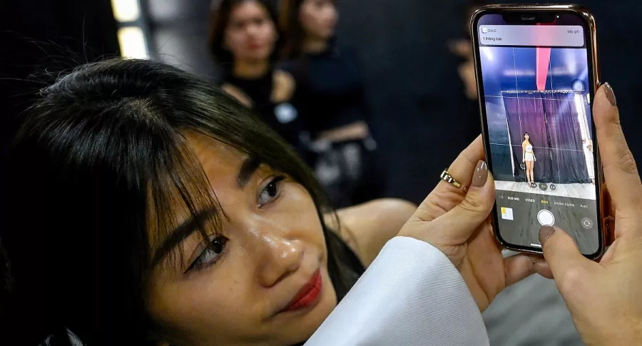 Imagen de mujer mirando un celular ilustra artículo Google anuncia teléfonos Android que funcionan con gestos faciales