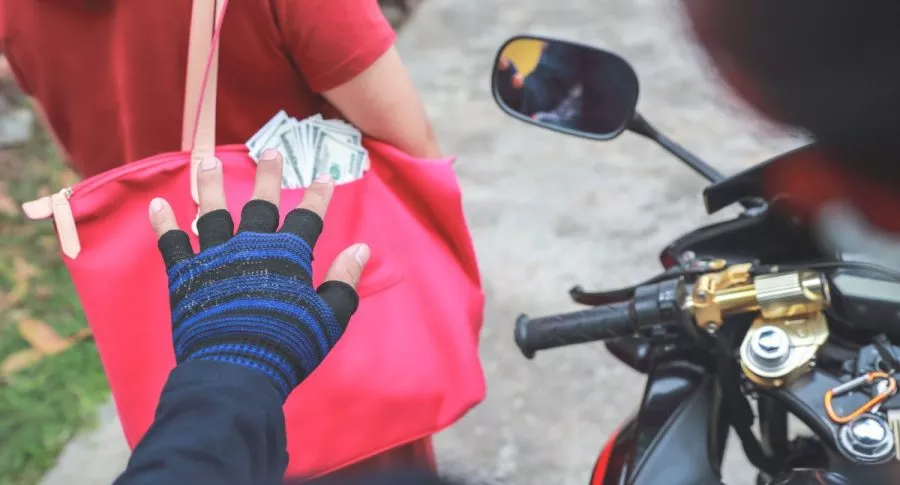 Ladrón en moto a punto de robar bolso de una mujer.