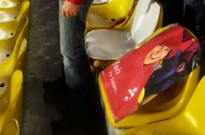 Foto con la fotografía de esposa fallecida de periodista en estadio, en nota de propuesta que hizo el hombre.