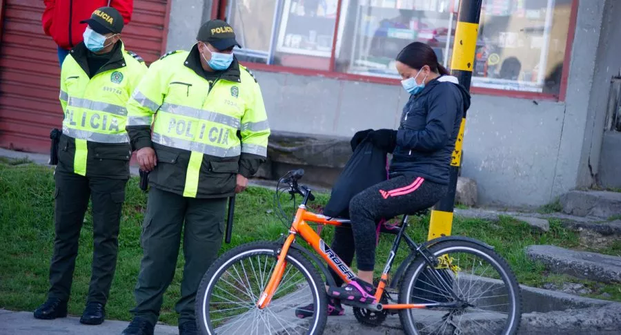 Policías junto a mujer en bicicleta en Bogotá ilustran nota de barrios donde más roban en la ciudad