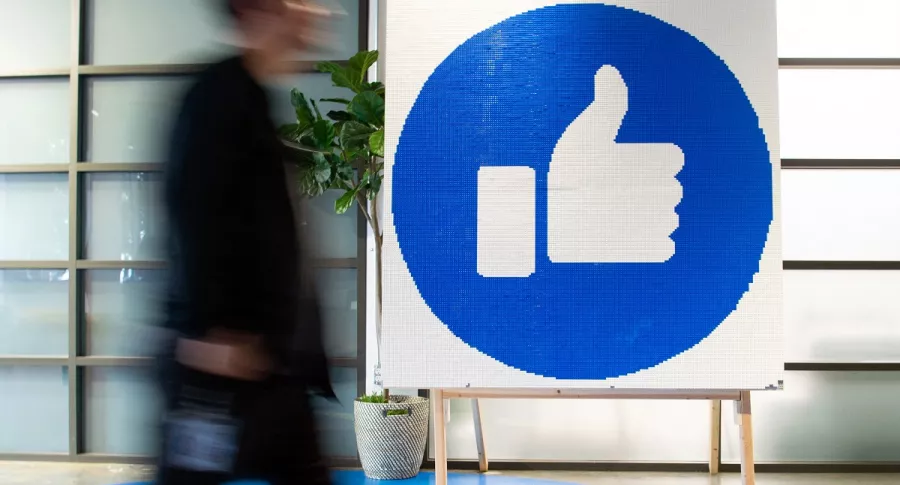 Imagen de persona caminando al lado de logo de Facebook ilustra artículo Facebook deberá pagar USD 14 millones por dar trabajo a extranjeros