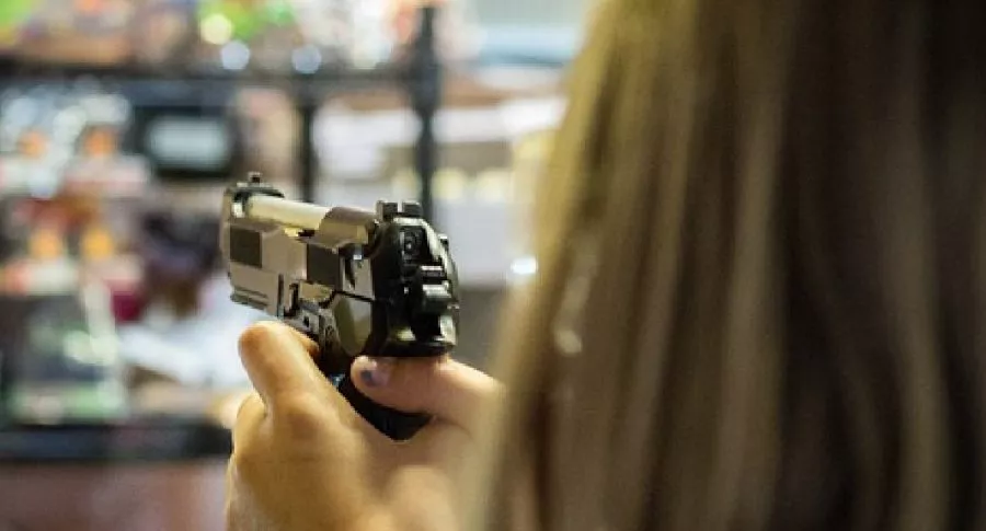 Imagen de una mujer sosteniendo y apuntando con una pistola