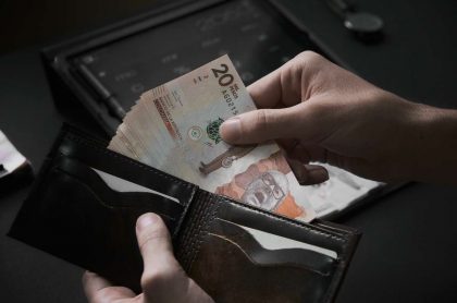 Foto de persona con billetes de pesos colombianos en billetera, en nota de cómo ahorrar en Colpensiones con menos del salario mínimo.
