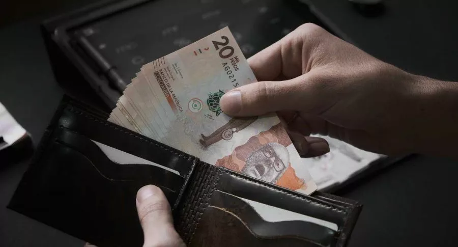 Foto de persona con billetes de pesos colombianos en billetera, en nota de cómo ahorrar en Colpensiones con menos del salario mínimo.