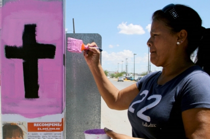 Imagen de mujer pintando una cruz ilustra artículo Más de 4.000 mujeres víctimas de feminicidio en 2020 en A. Latina y el Caribe