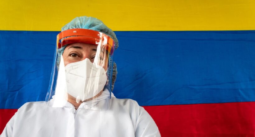 Una trabajadora de la salud con una bandera de Colombia a sus espaldas, representando los retos del año para el país.