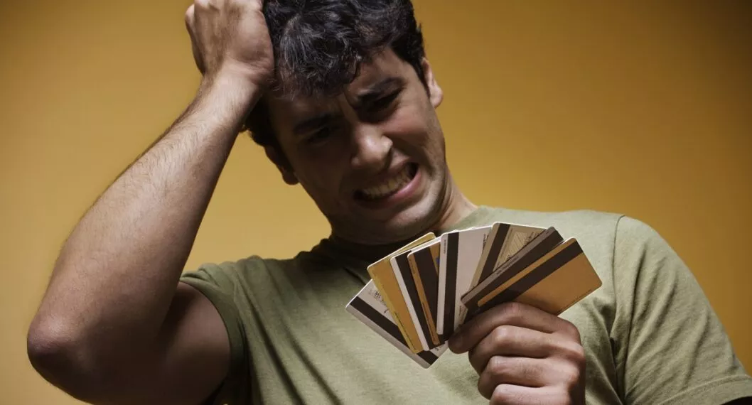 Persona con tarjetas de crédito en la mano a propósito del informe que dice que más de la mitad de colombianos tiene deudas.