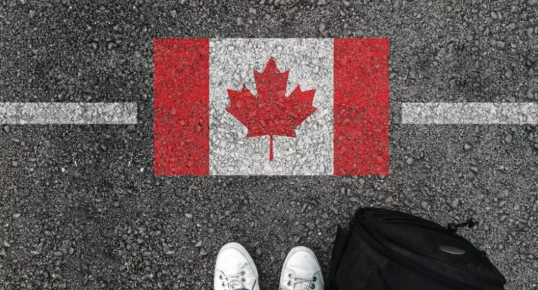 Persona con maleta al lado de la bandera de Canadá ilustra nota sobre requisitos para sacar la visa de ese país 