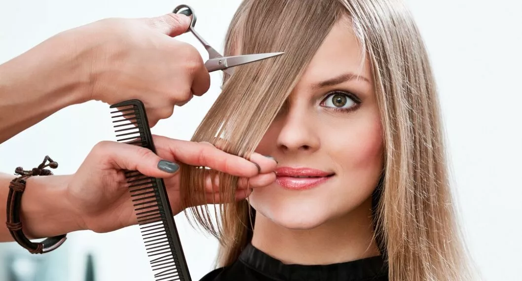 Mujer cortándose el cabello ilustra nota sobre fechas ideales para cortar el pelo y que crezca rápido y fuerte