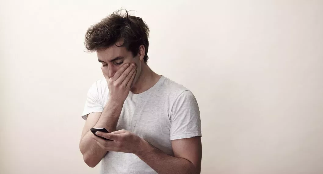 Hombre preocupado mirando el celular ilustra nota sobre cómo consultar si está reportado en Datacrédito