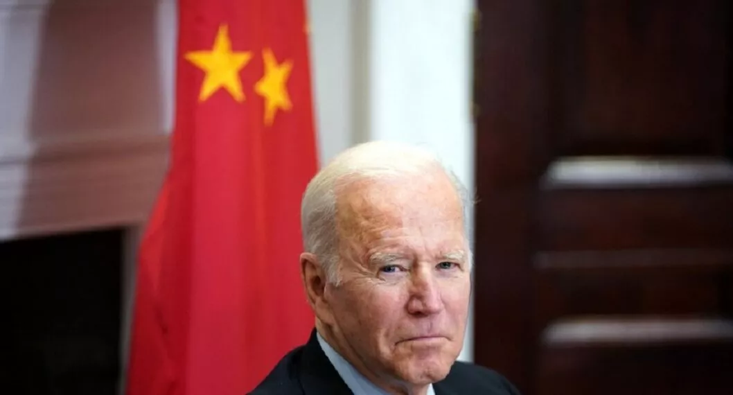Presidente Joe Biden con una bandera de China al fondo. 