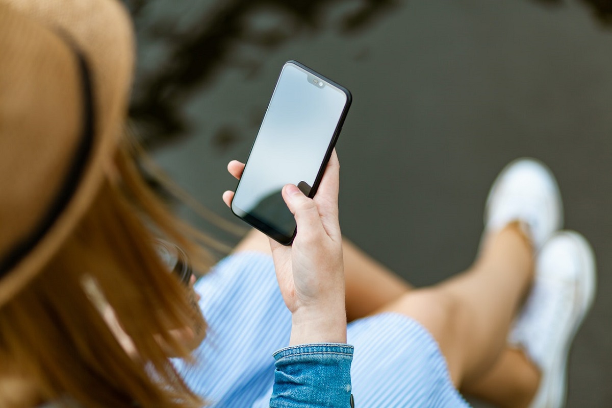 Imagen de mujer con celular en la mano ilustra artículo Los chatbots son los nuevos colaboradores consentidos de las compañías
