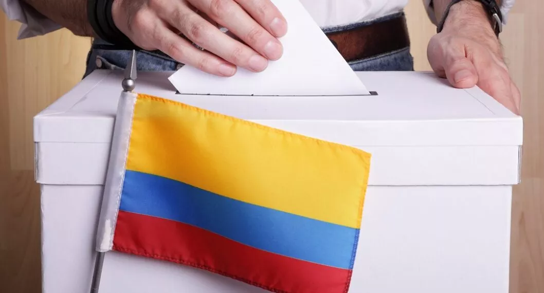 Ciudadano votando en urna con bandera de Colombia, a propósito del mediodía que puede pedir y otros beneficios por haber votado en elecciones de marzo 13 de 2022.