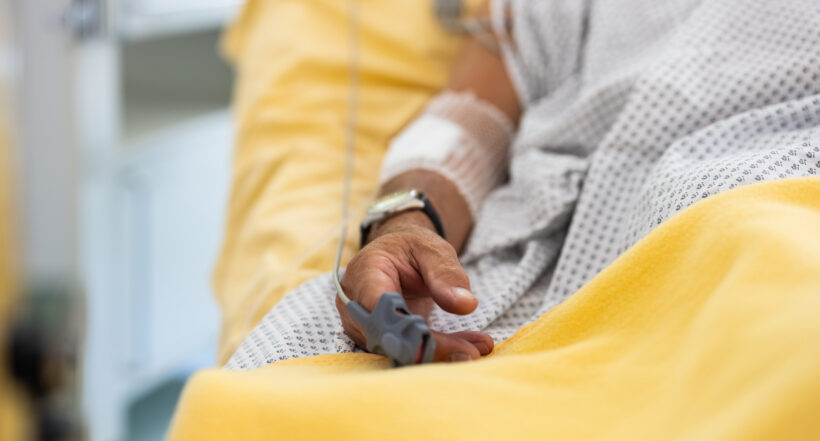 Close-up of a male patient's hand in a hospital bed with oximeter. Senior man admitted hospital.