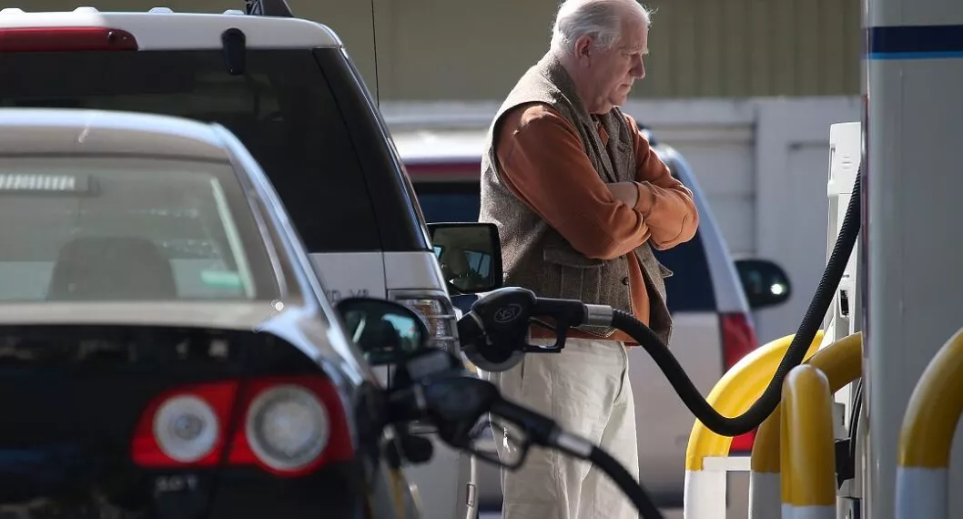 Carros en estación de gasolina y un hombre esperando ilustran nota sobre cómo ahorrar gasolina