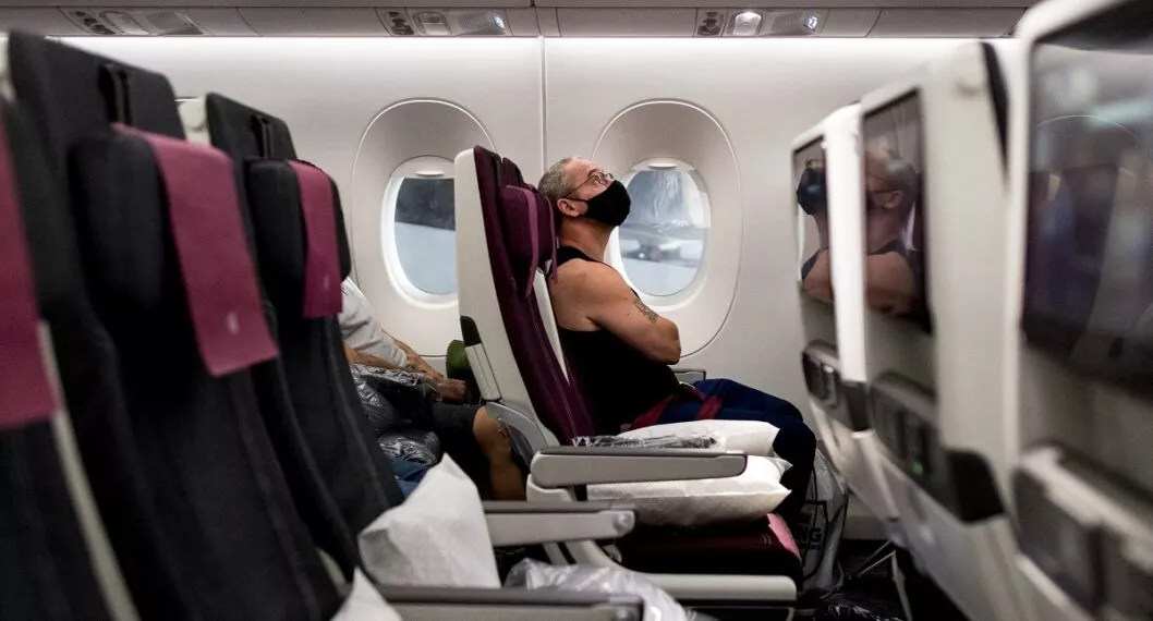 Imagen de pasajero con tapabocas en avión ilustra artículo Se cayó el tapabocas en aviones y otros medios de transporte público de EE.UU.