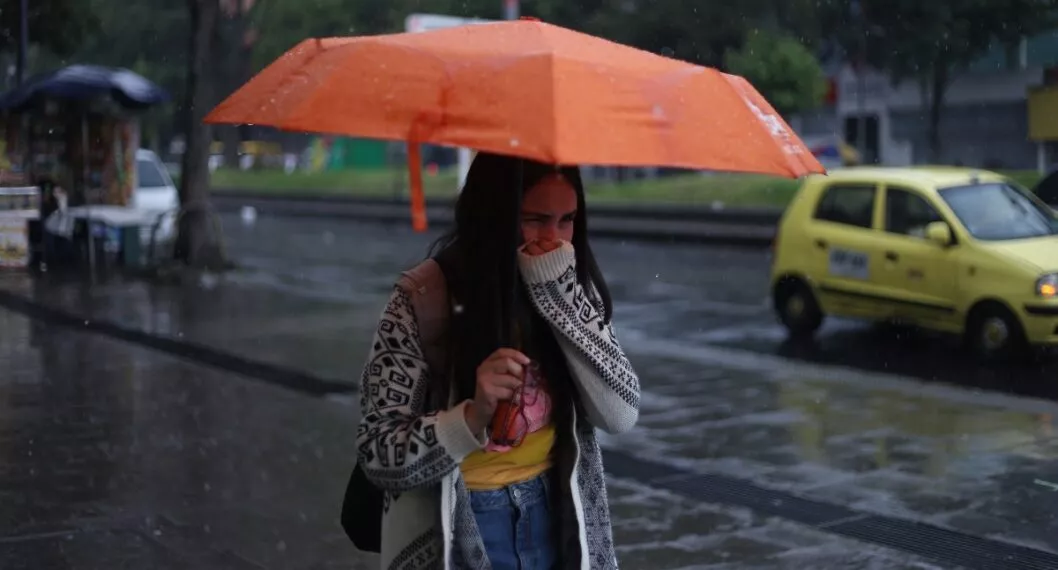 Mujer con sombrilla ilustra nota sobre hasta cuándo lloverá en Colombia, según el Ideam