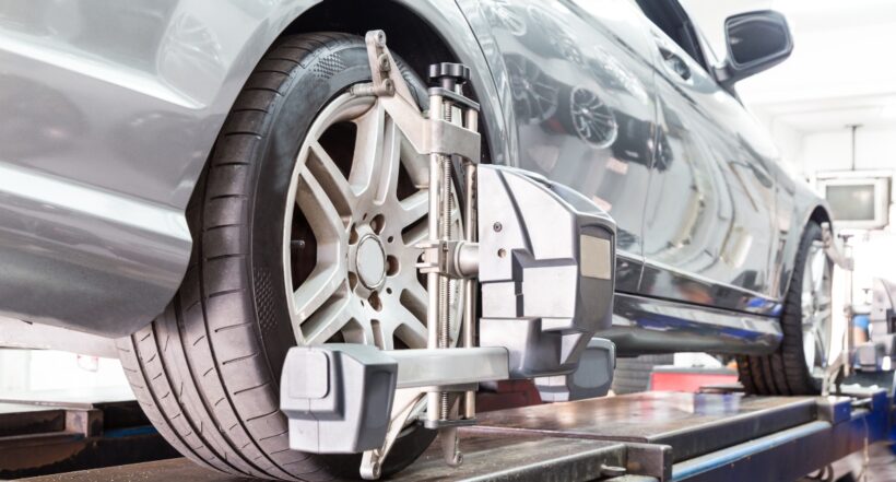 Closeup of tire clamped with aligner undergoing auto wheel alignment in garage