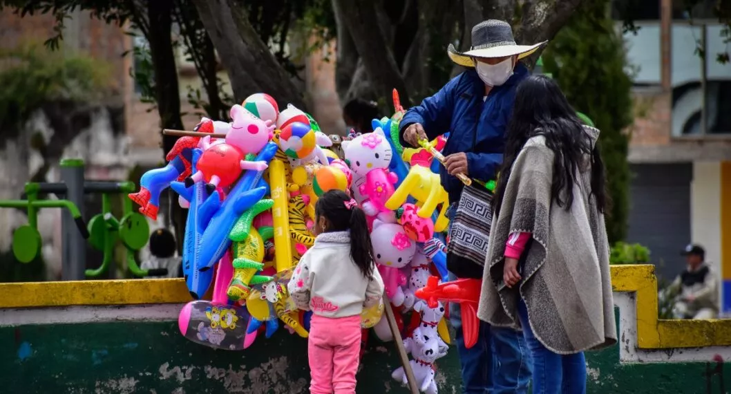 A mom and her daughter buy rubber balloons and toys to a street vendor in Cumbal - Nariño, Colombia on August 15, 2021.