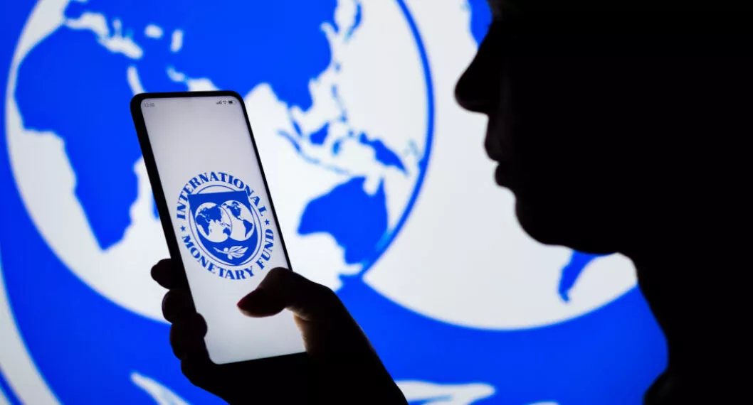 BRAZIL - 2022/04/06: In this photo illustration, a woman's silhouette holds a smartphone with the International Monetary Fund (IMF) logo displayed on the screen and in the background. (Photo Illustration by Rafael Henrique/SOPA Images/LightRocket via Getty Images)